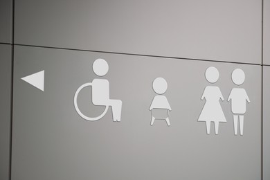 Image of White public toilet sign with arrow showing direction on wall