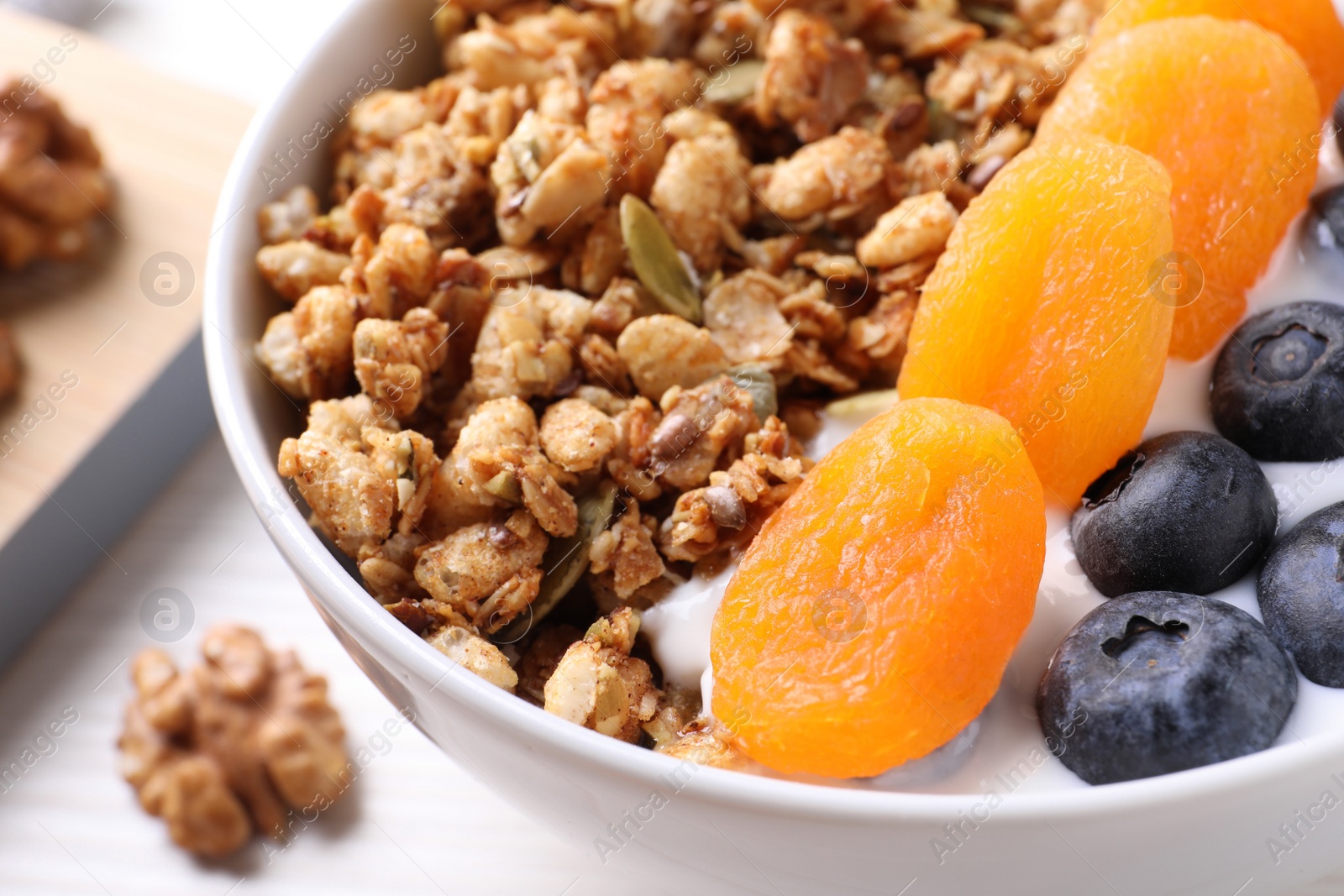 Photo of Delicious granola with fruits on white table, closeup