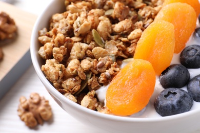 Delicious granola with fruits on white table, closeup