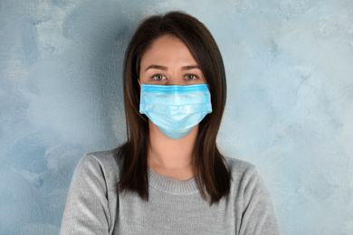 Photo of Woman with disposable mask on face against light blue background