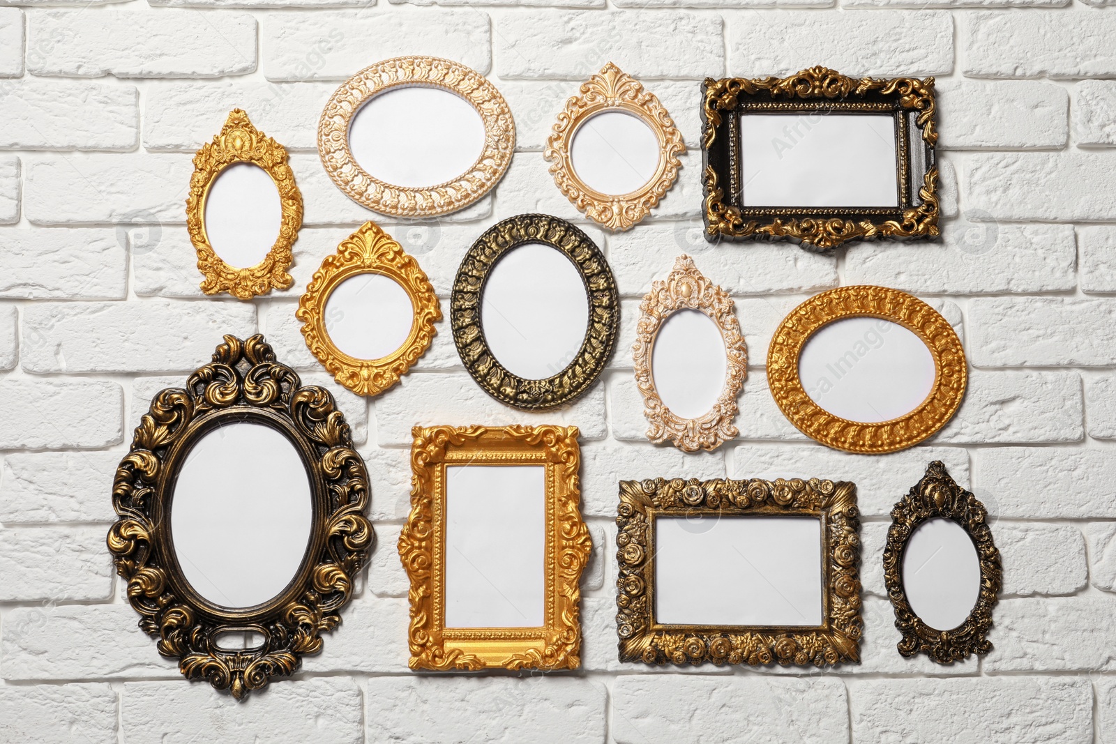 Photo of Blank vintage frames hanging on white brick wall. Mockup for design