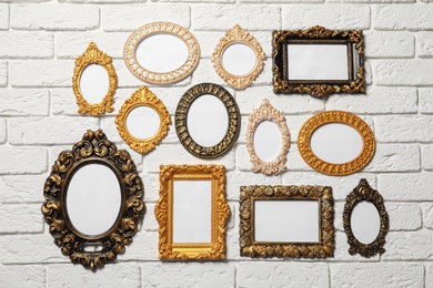 Photo of Blank vintage frames hanging on white brick wall. Mockup for design