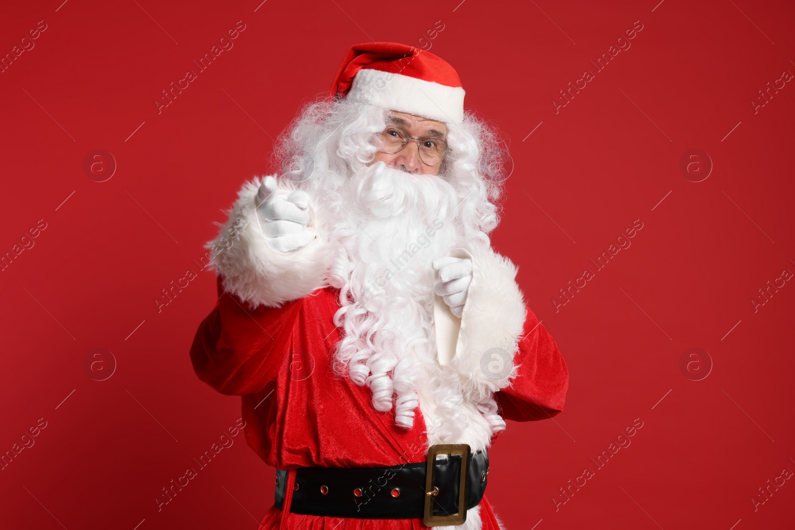 Photo of Merry Christmas. Santa Claus pointing at something on red background