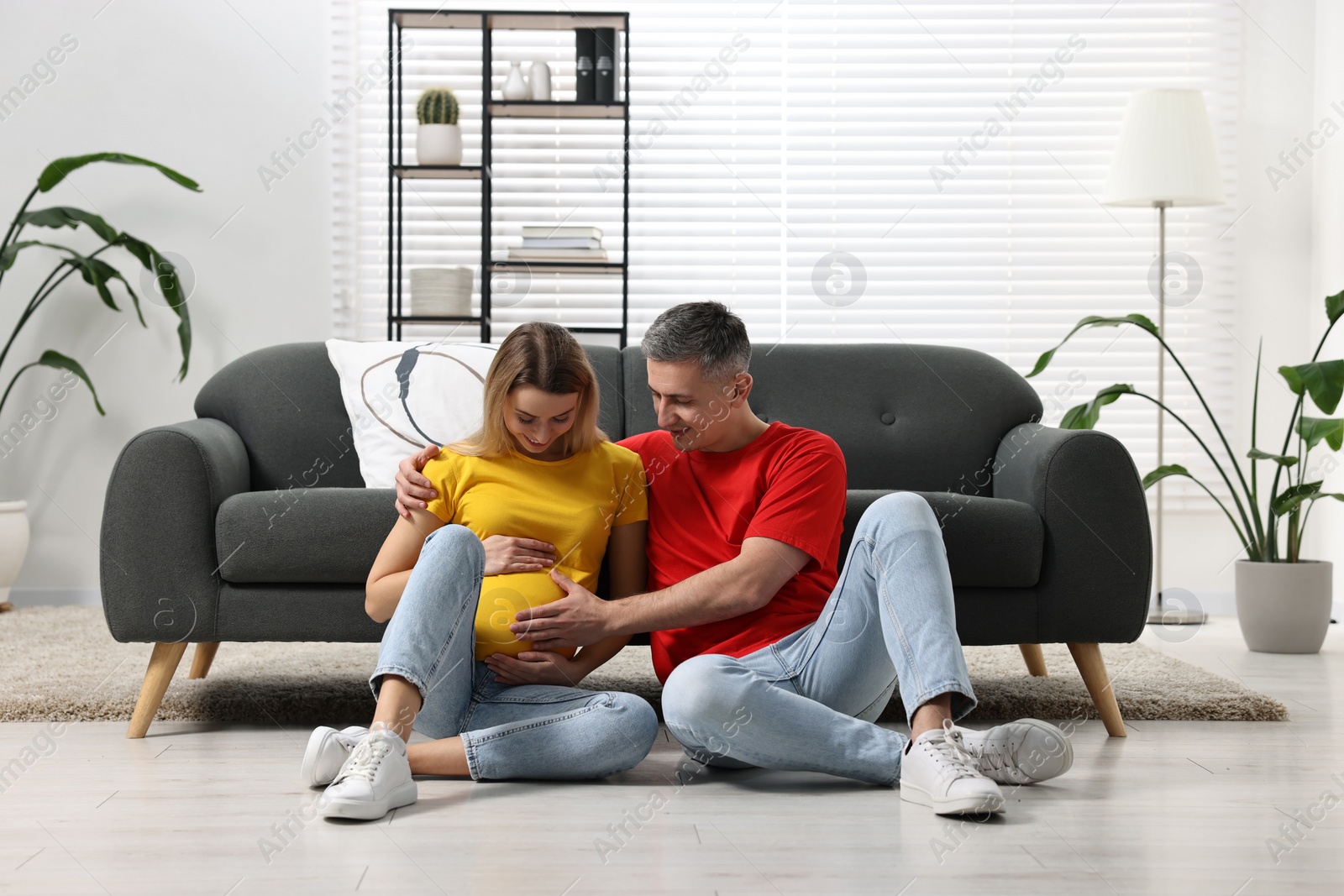 Photo of Young family housing concept. Pregnant woman with her husband on floor at home