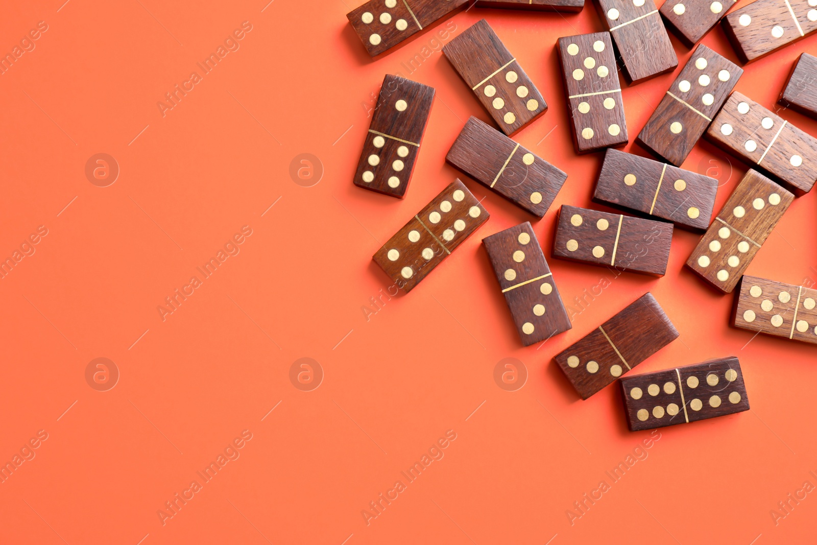 Photo of Wooden domino tiles on coral background, flat lay. Space for text