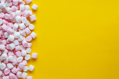 Photo of Delicious puffy marshmallows on yellow background, flat lay. Space for text