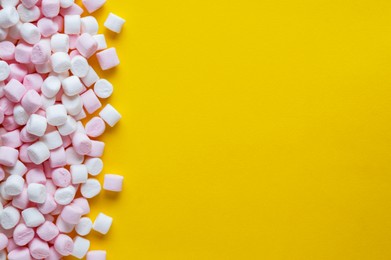 Delicious puffy marshmallows on yellow background, flat lay. Space for text