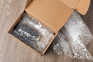 Jar in cardboard box and bubble wrap on wooden table, top view