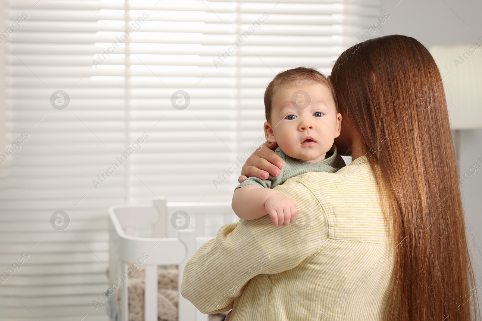 Photo of Mother holding her cute newborn baby at home, space for text