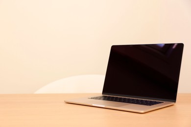 Photo of Modern laptop on wooden table. Space for text