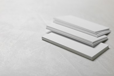 Blank business cards on light grey textured table, closeup. Mockup for design