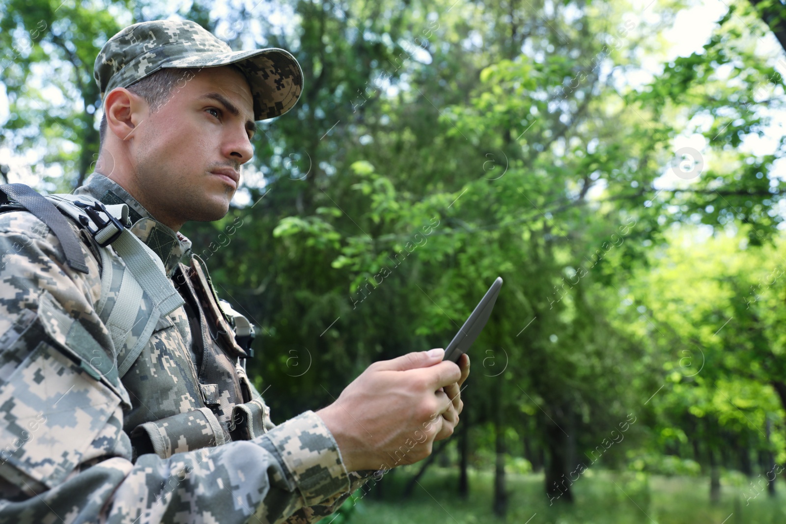 Photo of Soldier with backpack using tablet in forest