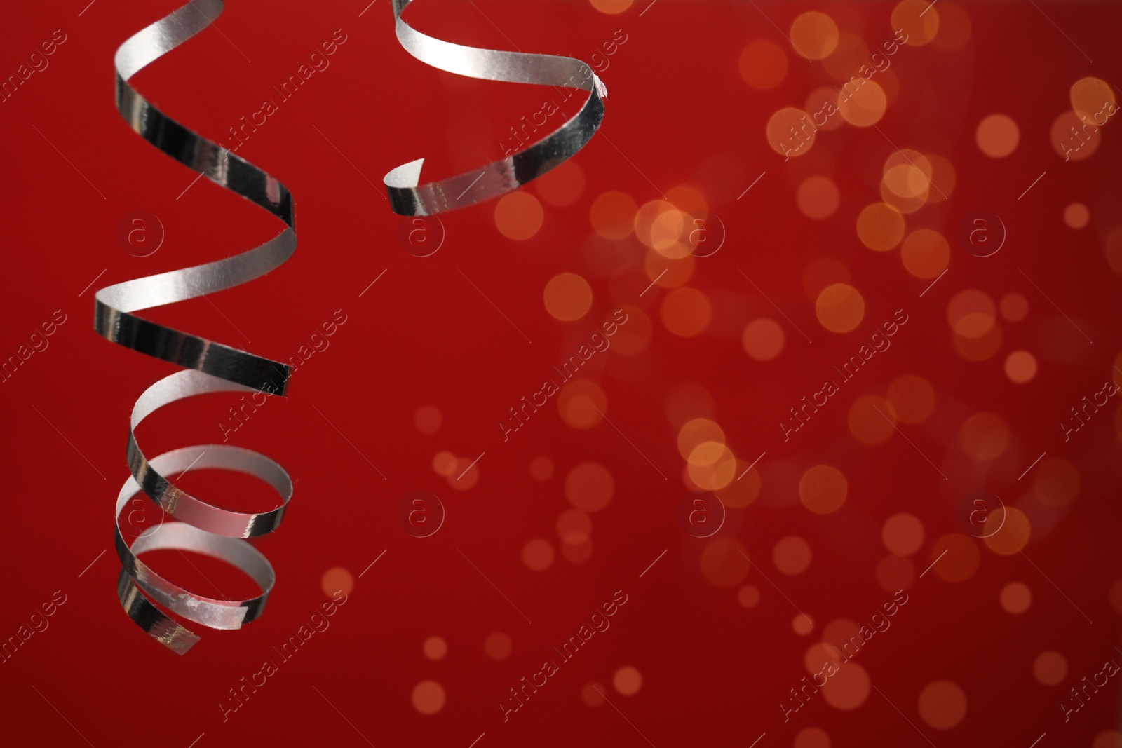 Photo of Shiny serpentine streamers against blurred lights. Space for text