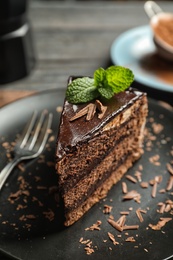 Plate with slice of chocolate cake and fork on table, closeup