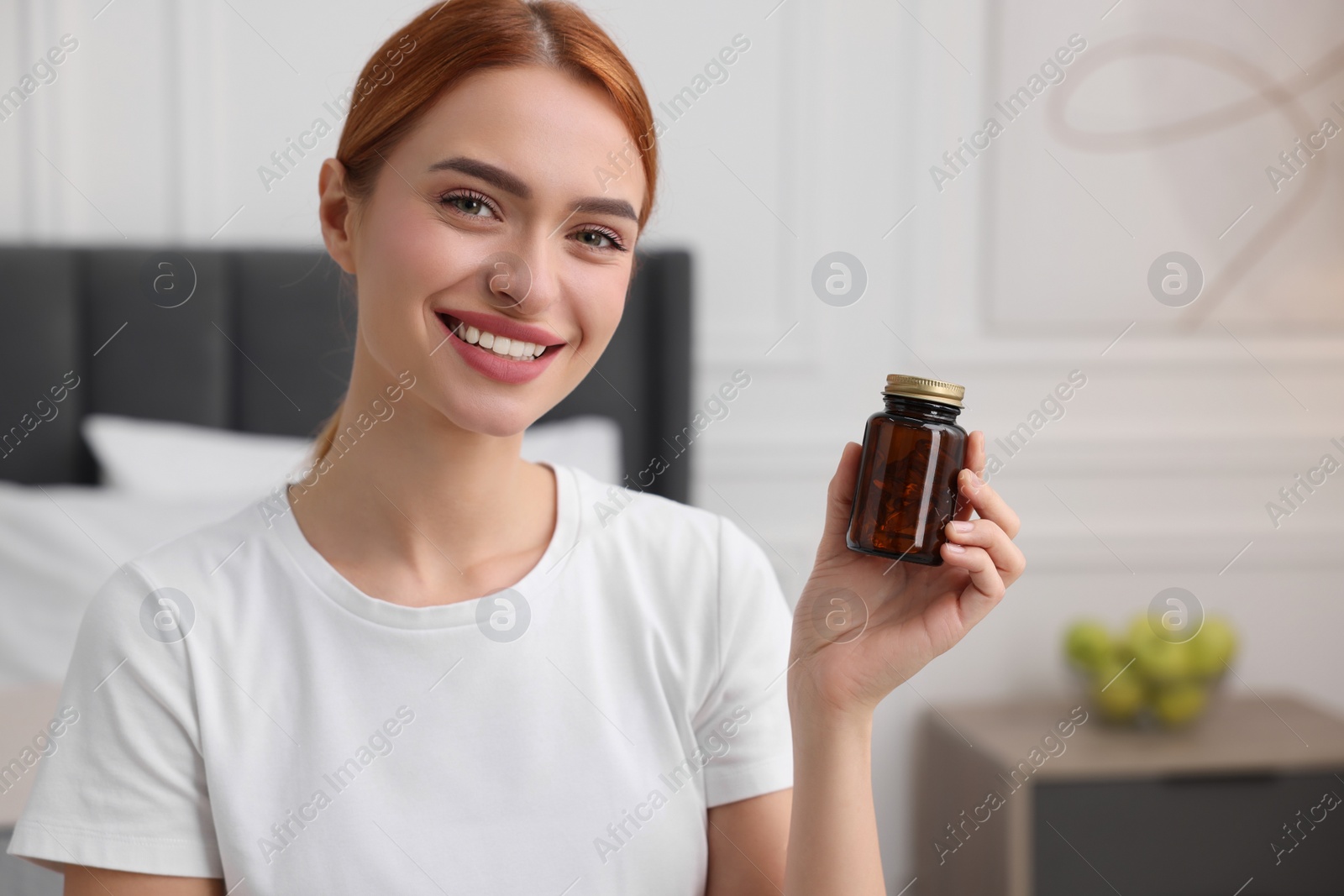Photo of Happy young woman with bottle of pills in room, space for text. Weight loss