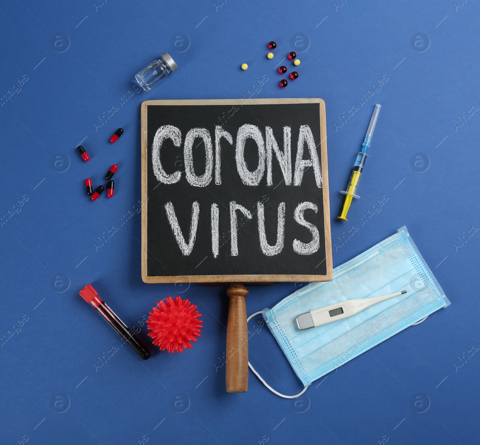 Photo of Chalkboard with words CORONA VIRUS, test tube and syringe on blue background, flat lay