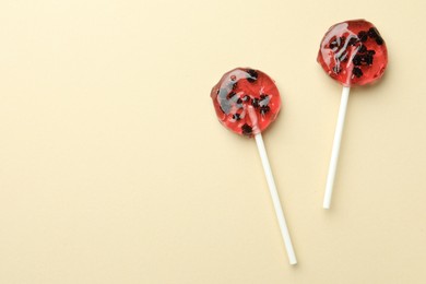 Photo of Sweet colorful lollipops with berries on beige background, flat lay. Space for text