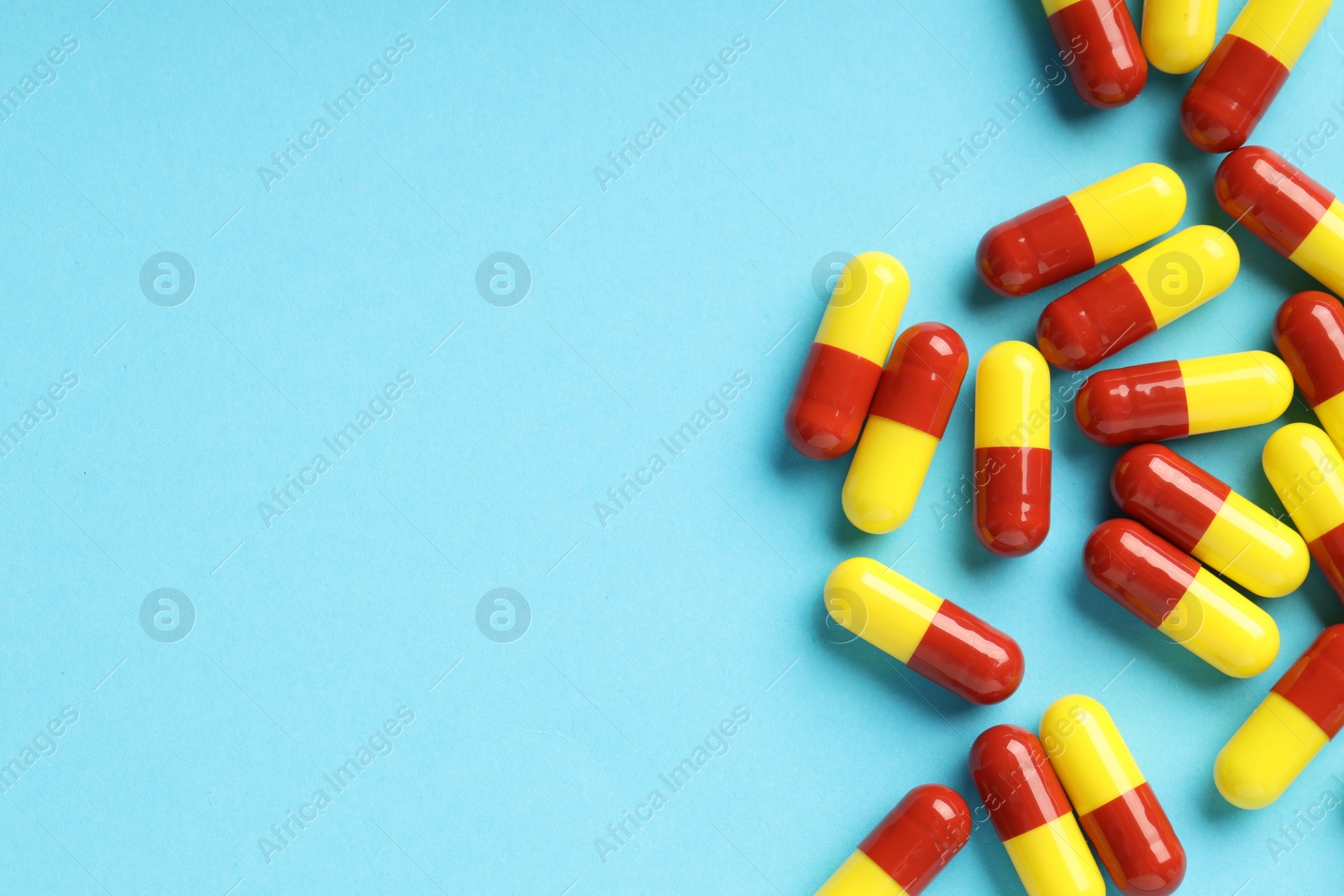 Photo of Many antibiotic pills and space for text on light blue background, top view. Medicinal treatment