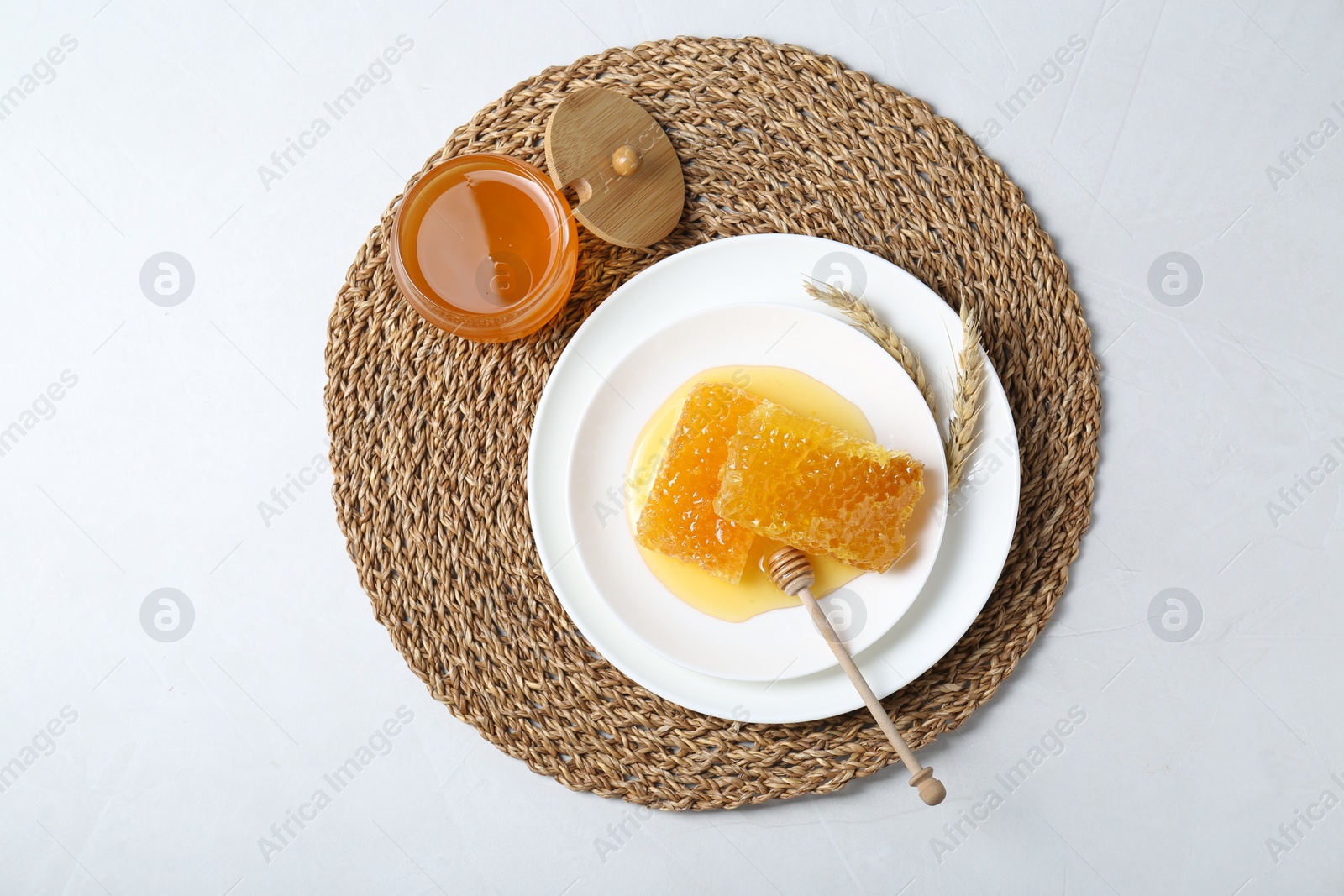 Photo of Natural honeycombs with tasty honey and dipper on white table, top view