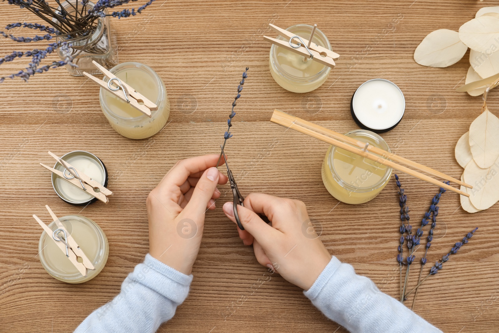 Photo of Woman making aromatic candles at wooden table, top view