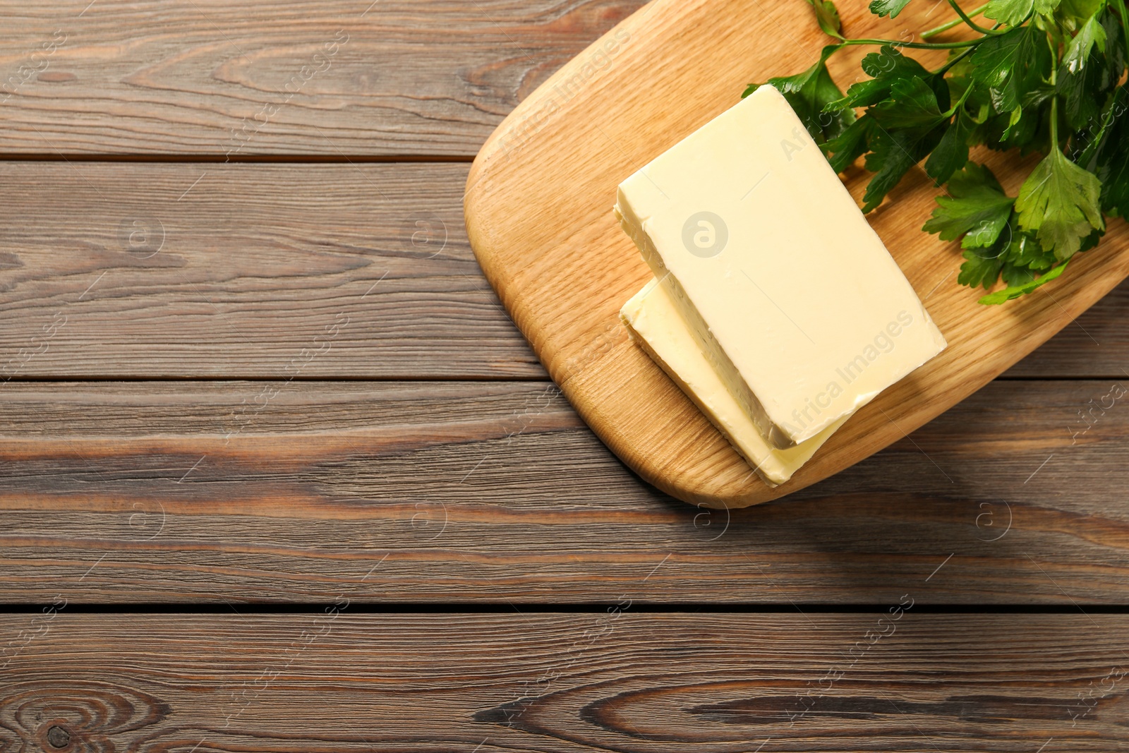 Photo of Tasty butter and parsley on wooden table, top view. Space for text