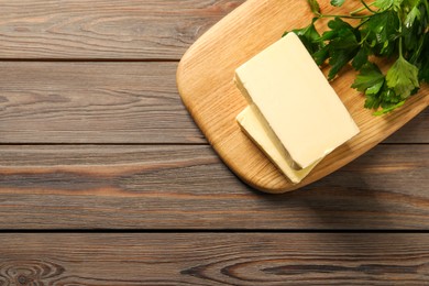 Tasty butter and parsley on wooden table, top view. Space for text