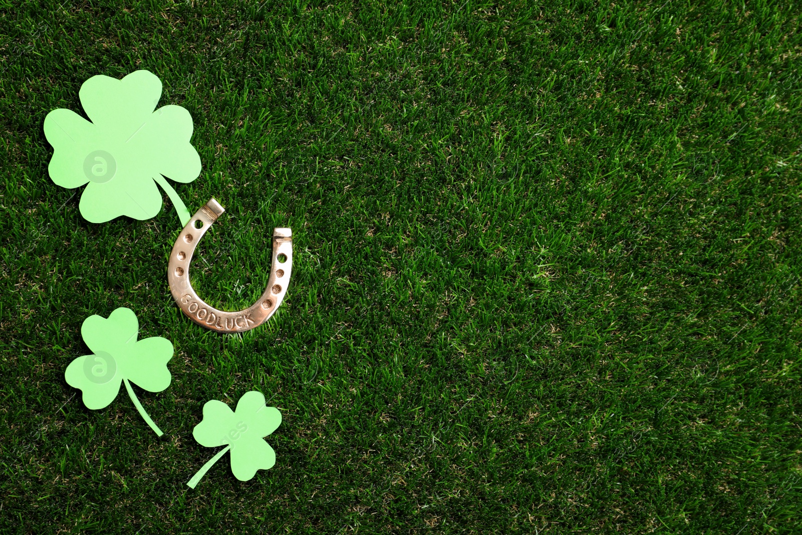 Photo of Flat lay composition with horseshoe on grass, space for text. St. Patrick's Day celebration