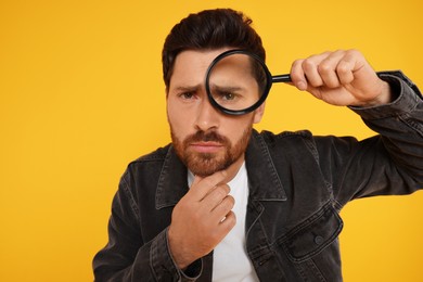Photo of Man looking through magnifier glass on yellow background