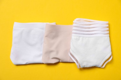 Photo of Stylish folded women's underwear on yellow background, flat lay