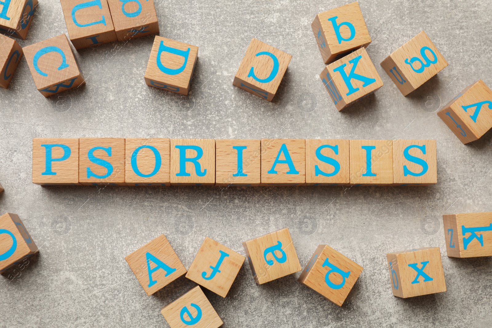 Photo of Word Psoriasis made of wooden cubes with letters on light gray textured table, flat lay