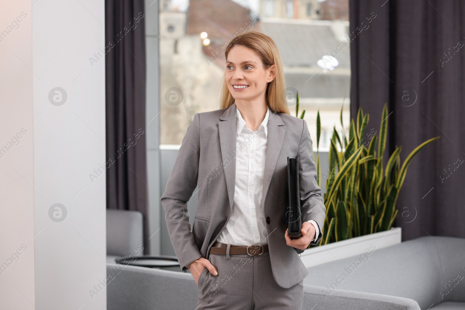 Photo of Happy real estate agent with leather portfolio indoors