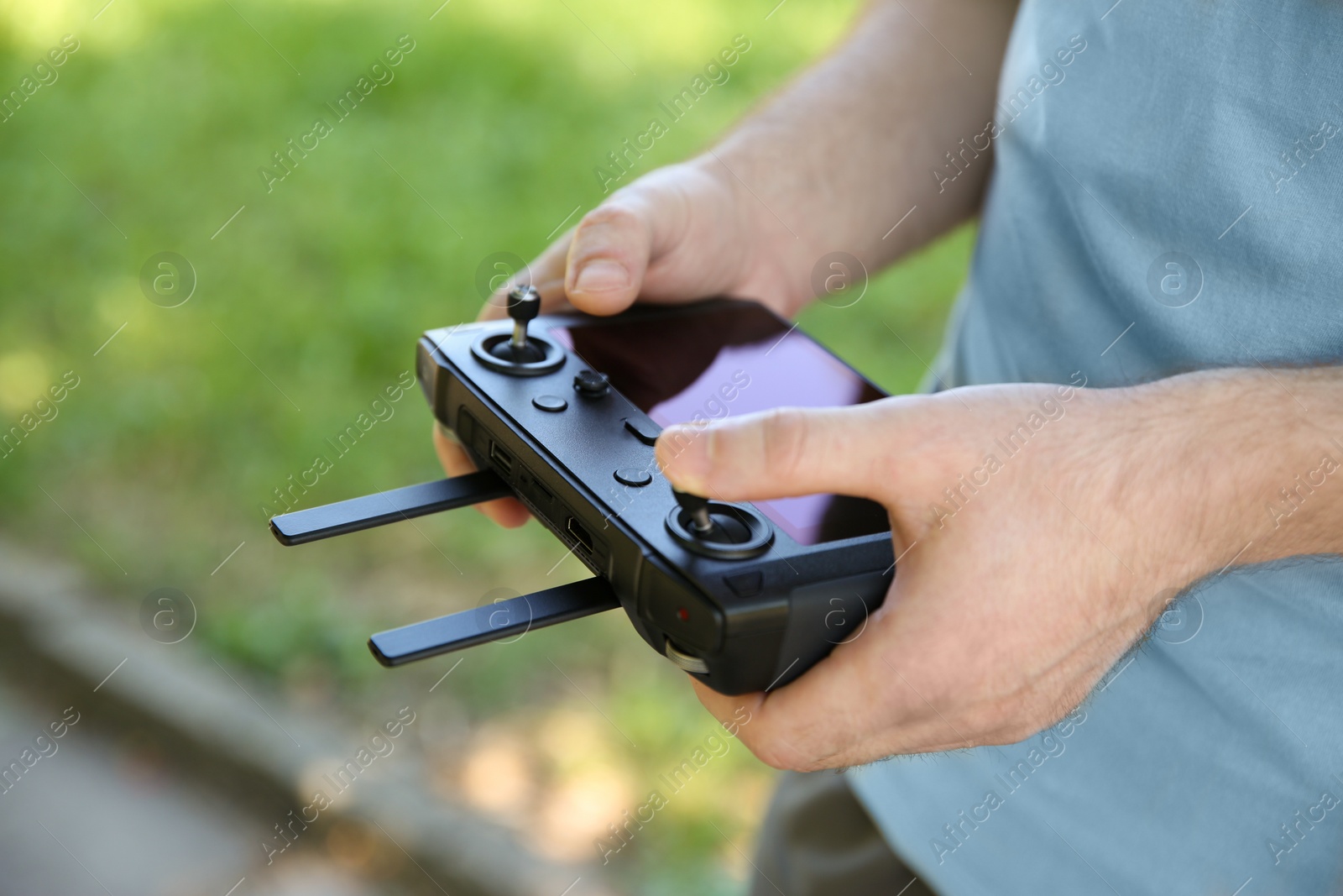 Photo of Man holding new modern drone controller outdoors, closeup of hands