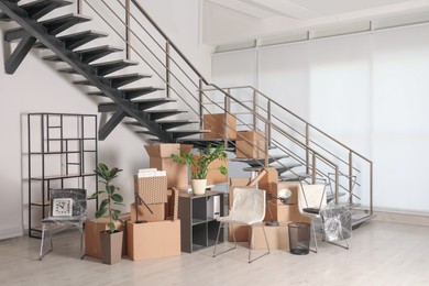 Photo of Cardboard boxes with packed stuff near stairs in office. Moving day