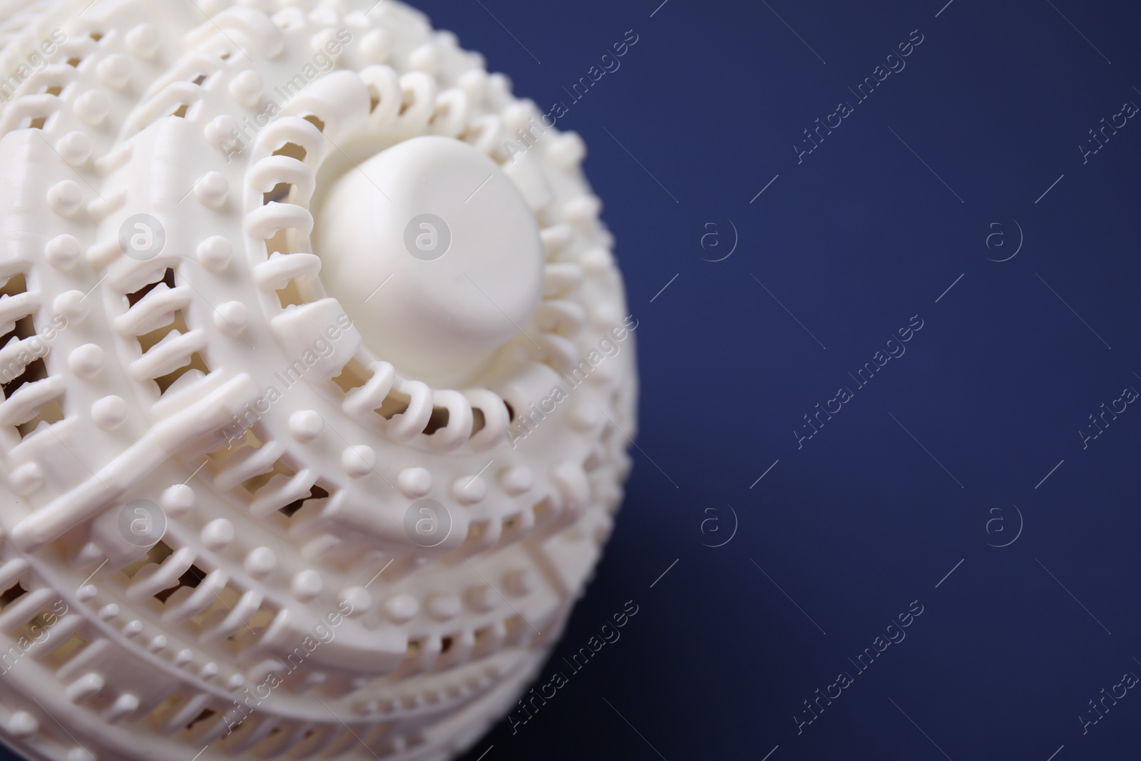 Photo of Laundry dryer ball on dark blue background, closeup. Space for text