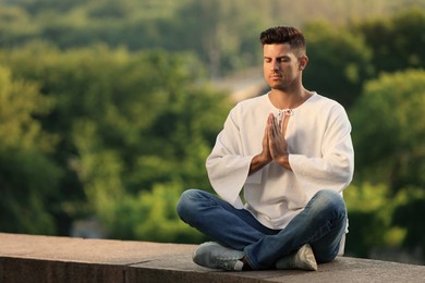 Photo of Man meditating outdoors on summer day. Space for text