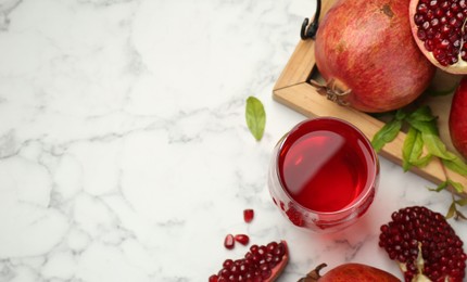 Photo of Tasty pomegranate juice in glass and fresh fruits on white marble table, flat lay. Space for text