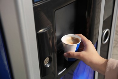 Photo of Woman taking paper cup with coffee from vending machine, closeup