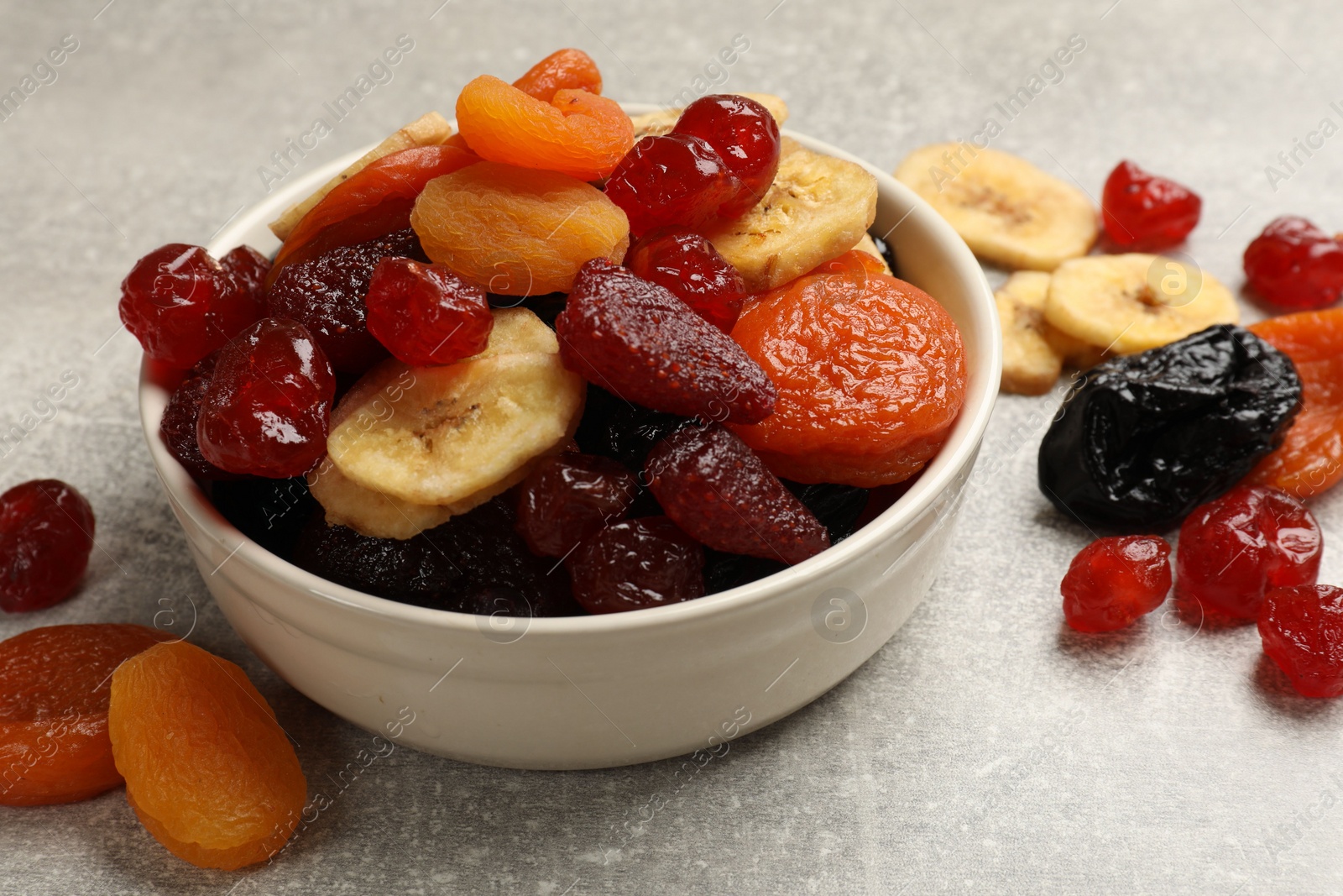 Photo of Mix of delicious dried fruits on grey table, closeup