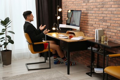Photo of Businessman in jacket and underwear having videocall on computer at home office