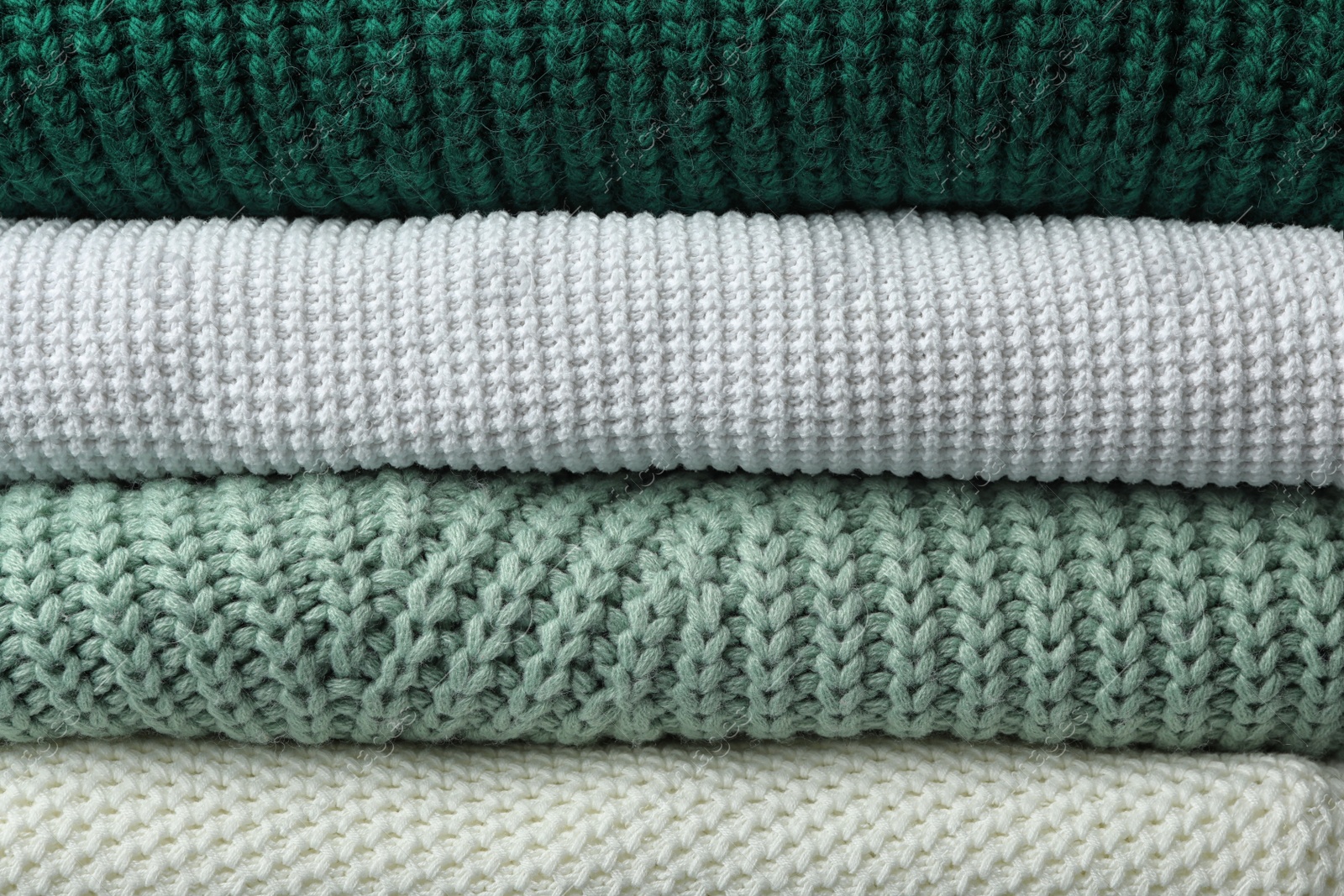 Photo of Stack of warm clothes as background, closeup. Autumn season