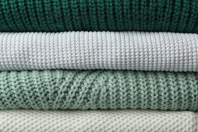 Photo of Stack of warm clothes as background, closeup. Autumn season