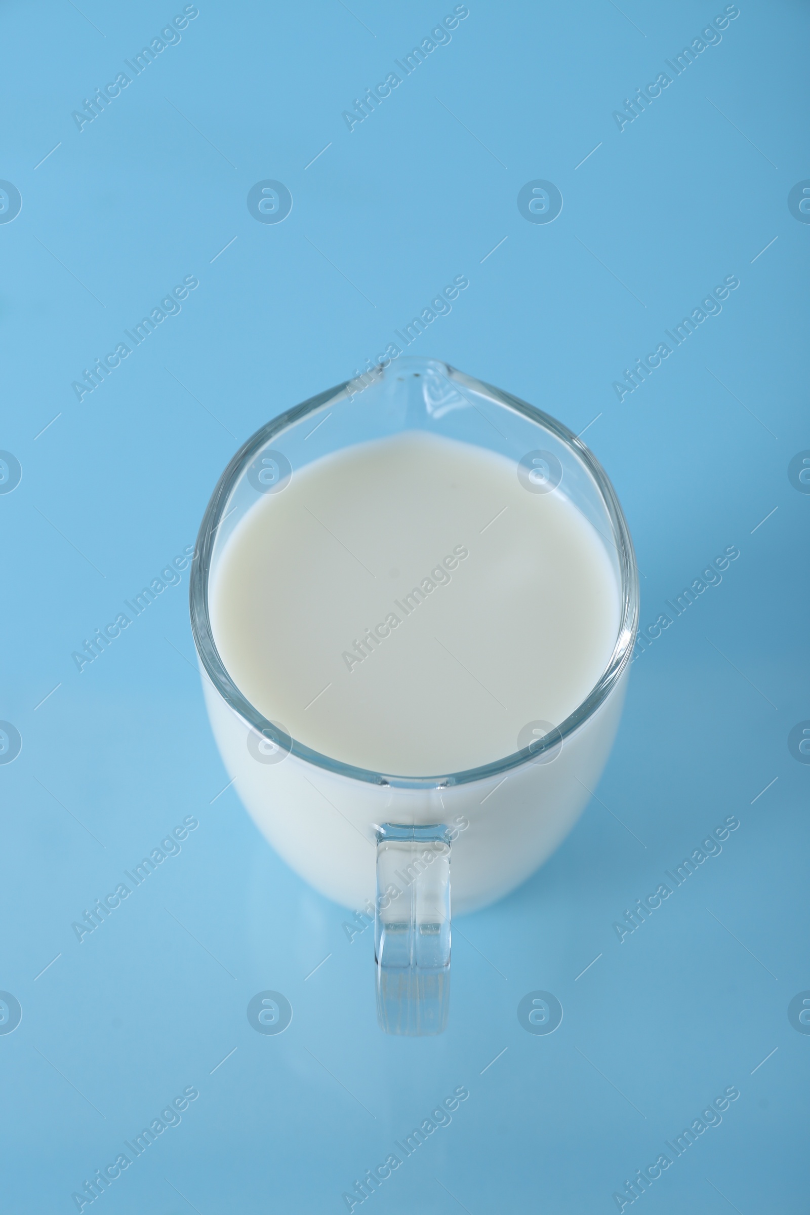 Photo of Jug of fresh milk on light blue background, above view