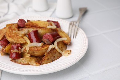 Photo of Delicious baked potato with thin dry smoked sausages and onion served on white table, closeup