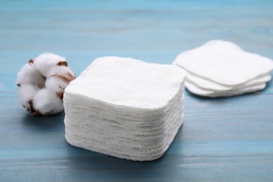 Stack of clean cotton pads on light blue wooden table, closeup