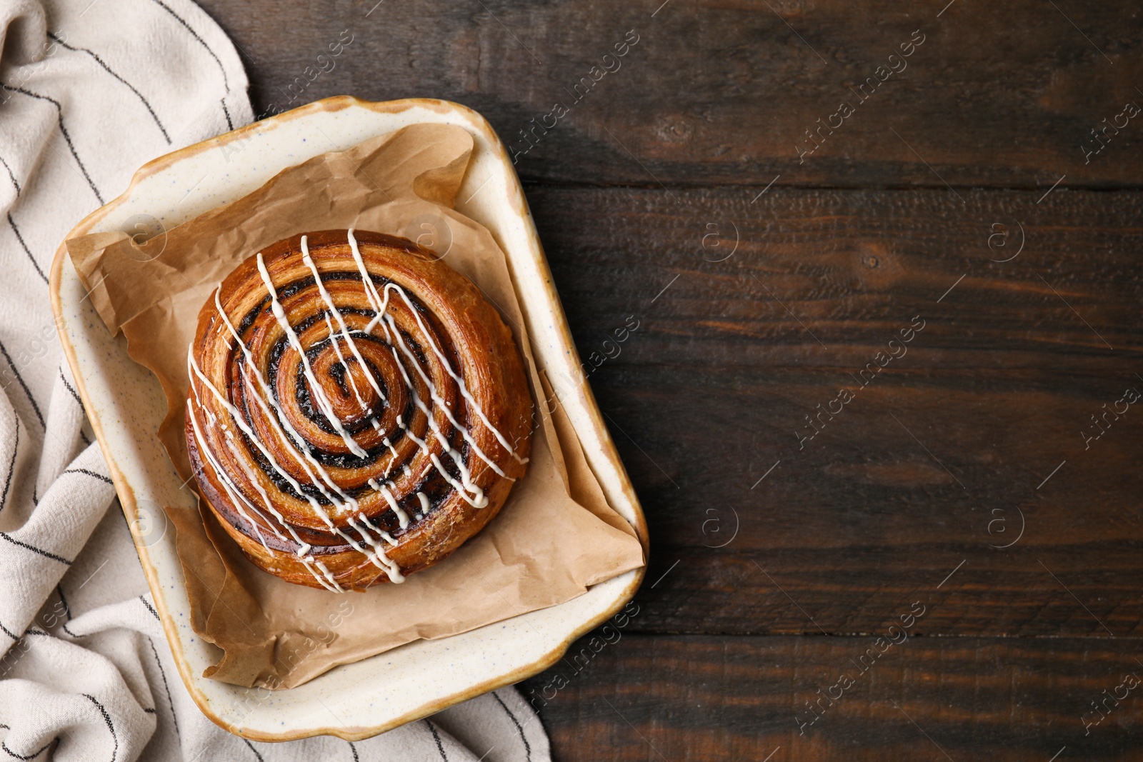 Photo of Sweet bun. Delicious roll with topping and poppy seeds on wooden table, top view. Space for text