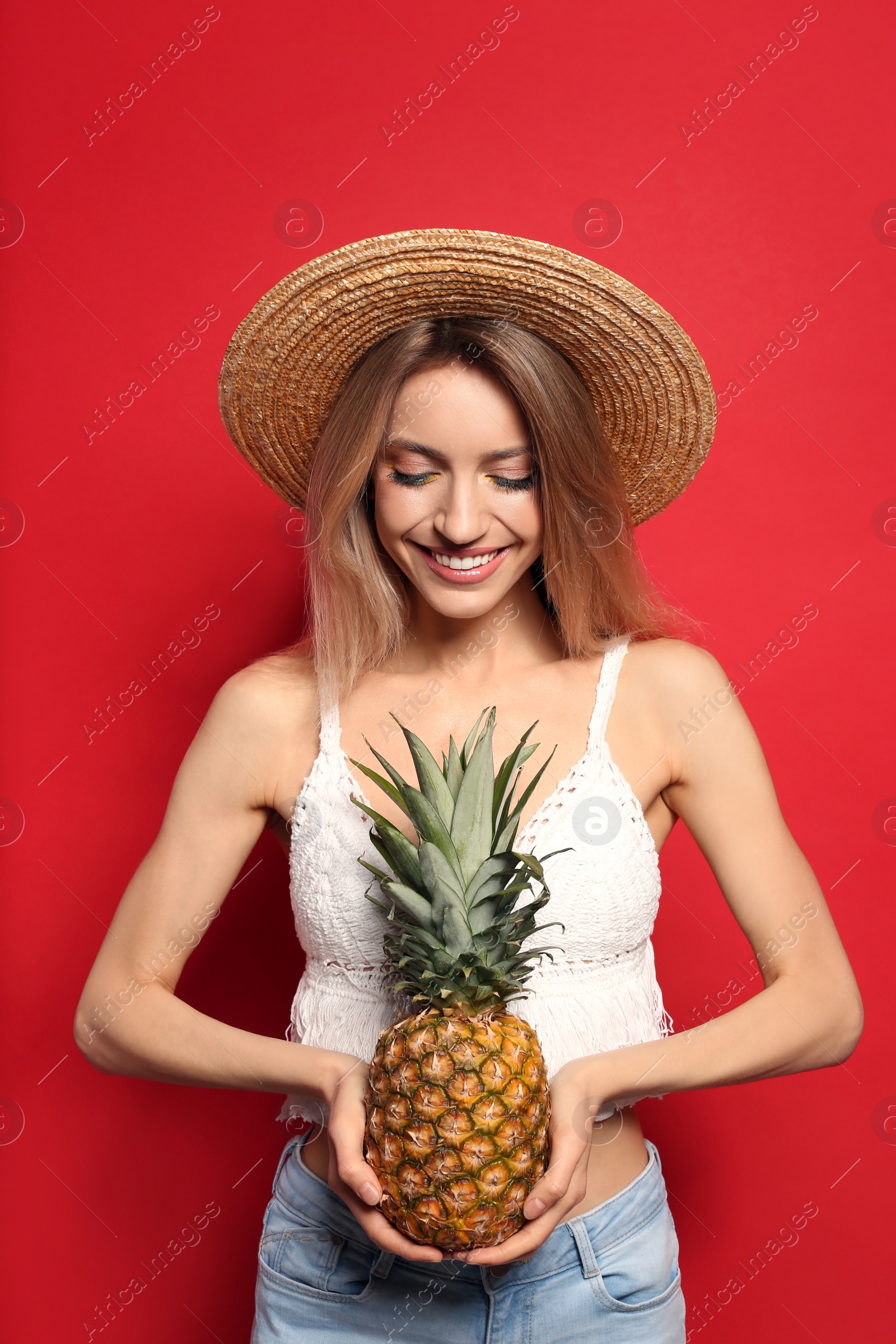 Photo of Young woman with fresh pineapple on red background. Exotic fruit