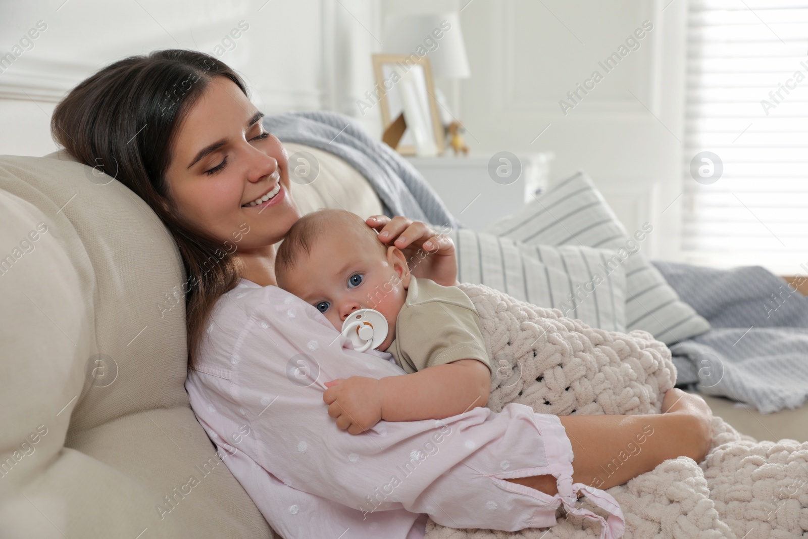 Photo of Young woman with her little baby on sofa at home