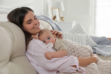 Young woman with her little baby on sofa at home