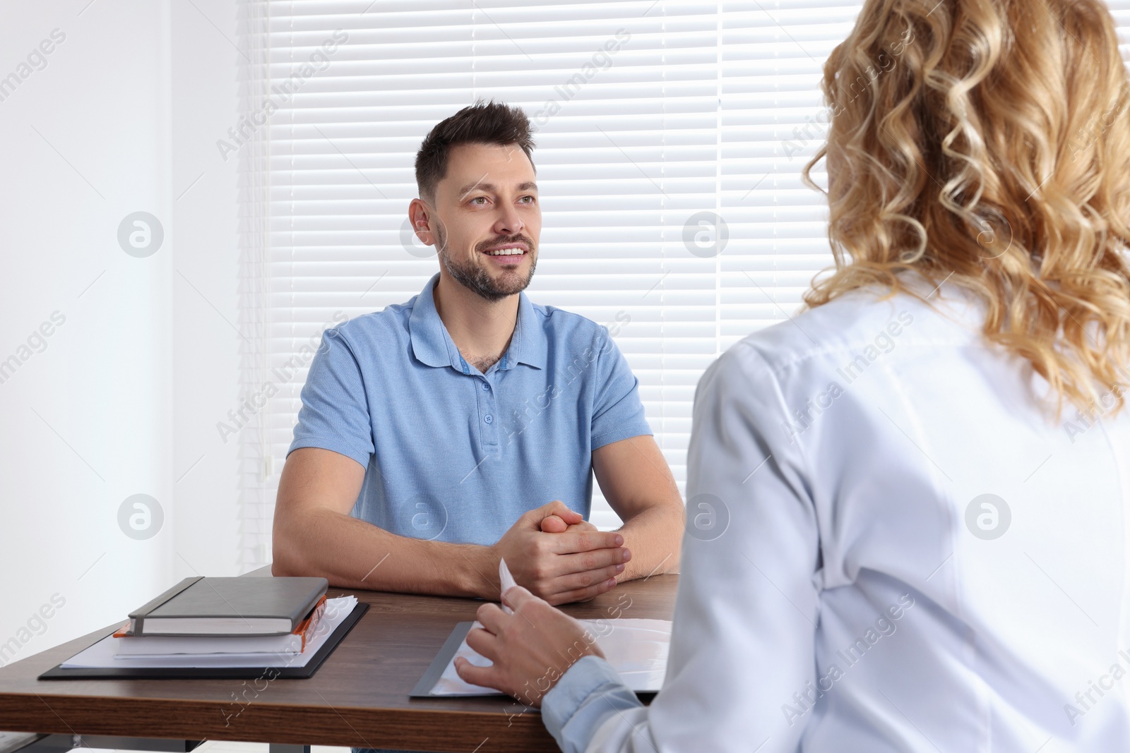 Photo of Doctor consulting patient at table in clinic