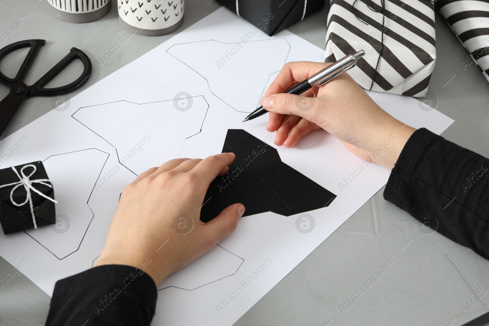 Photo of Woman making advent calendar at grey table, closeup